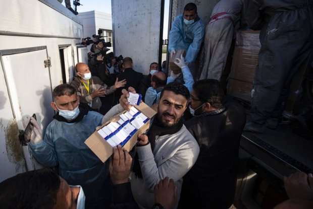 Workers unload boxes of the Sputnik V vaccine from a truck in the Gaza Strip